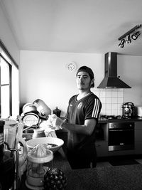 Portrait of man washing crockery in kitchen
