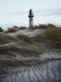 Lighthouse amidst buildings against sky