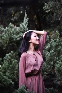 Beautiful young woman standing against trees