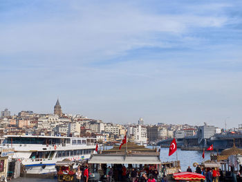 Group of people in city by river against sky