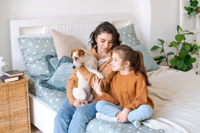 Happy mom and daughter play with their adorable wired jack russell terrier