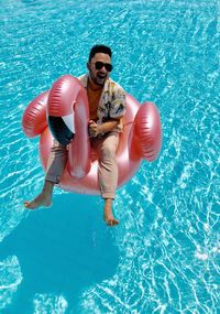 High angle view of man sitting on inflatable ring in swimming pool