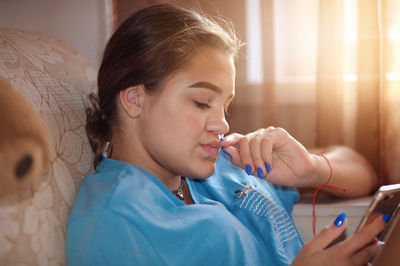 Close-up of teenage girl using mobile phone at home