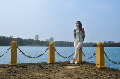 Woman standing by sea against clear sky