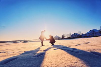 People sitting on land against clear sky during sunny day