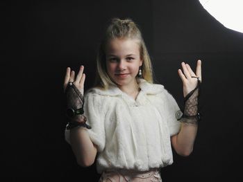 Portrait of girl standing against black background