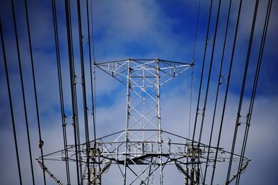 Low angle view of electricity pylon against blue sky