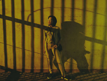 Full length of young woman standing against wall