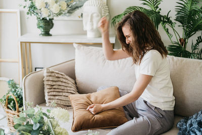 An angry woman screams into a pillow and slams her fists on the couch.