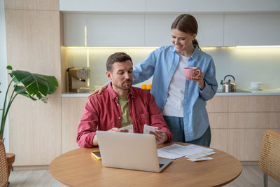 Side view of young woman using laptop while sitting on table