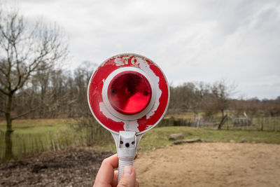 Close-up of hand holding red umbrella against the sky