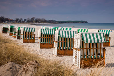 Hooded chairs at beach against sky