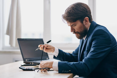 Side view of businessman using laptop at office