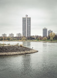 Scenic view of river by buildings against sky