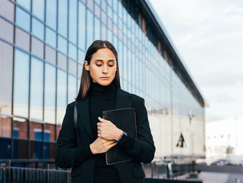 Portrait of young businesswoman standing in city