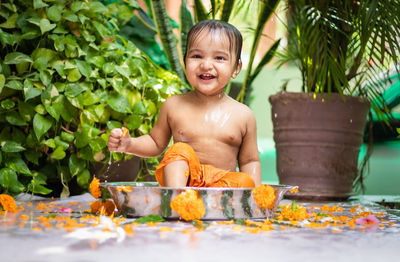 Cute toddler baby boy bathing in decorated bathtub at outdoor from unique perspective