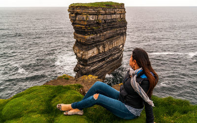 Woman sitting on rock by sea