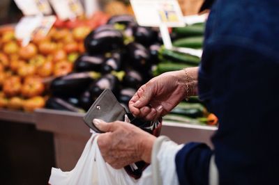 Midsection of woman buying vegetables at market