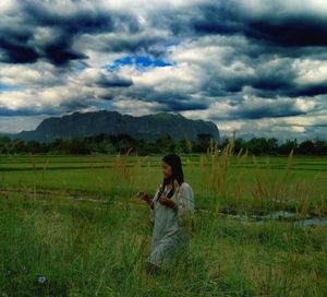 Full length of woman standing on field against sky