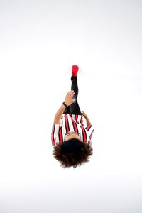 Person holding red ball on table against white background