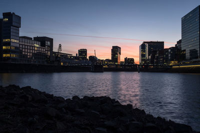 River by buildings against sky at dusk