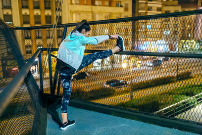 Full length of young woman sitting on railing