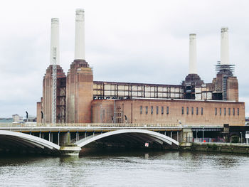 Bridge over river by buildings against sky in city