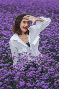Portrait of smiling young woman by purple flowering plants