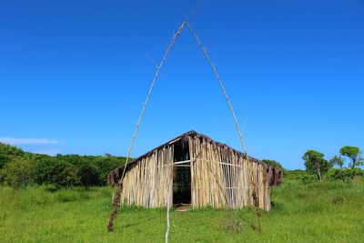 Abandoned built structure on field against clear blue sky