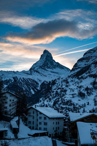 Snow covered houses and mountains against sky