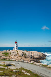 Lighthouse by sea against sky