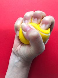 Cropped hand squeezing stress ball against red background