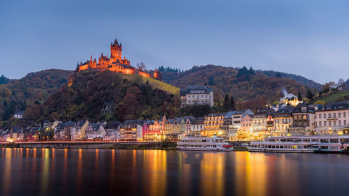 Buildings by river against sky