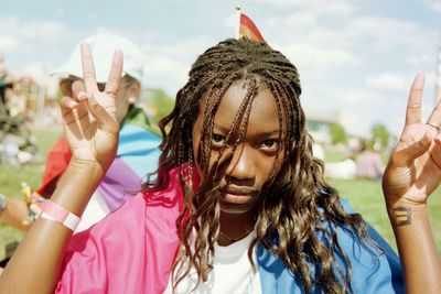 Portrait of young woman showing peace signs on sunny day