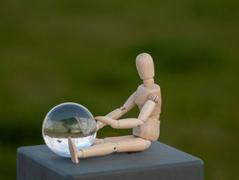 Close-up of figurine with crystal ball on retaining wall