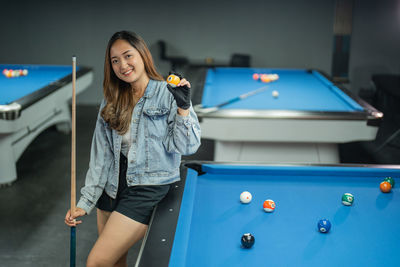 Portrait of happy girl playing pool
