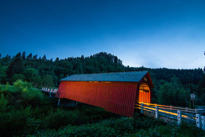 Illuminated covered walkway in forest at dusk