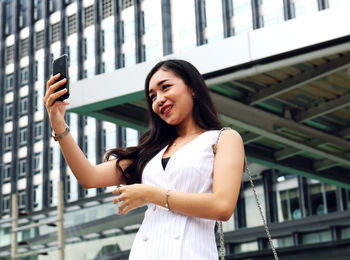 Portrait of smiling woman standing on mobile phone
