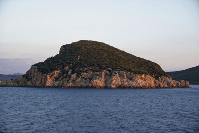 Scenic view of rocks by sea against sky