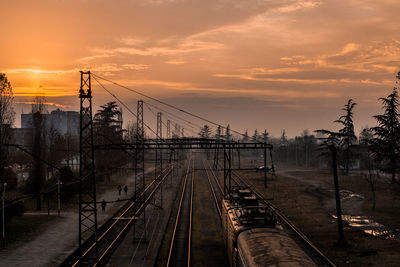Train on railroad tracks against sky during sunset