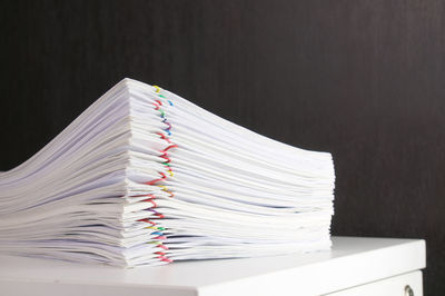 Close-up of stacked files on table against wooden wall