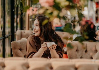 Young woman looking at camera while sitting in cafe