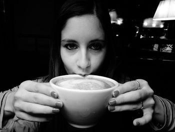 Close-up portrait of woman holding coffee cup