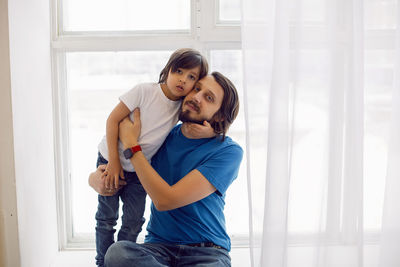 Father and son having fun sitting by the window