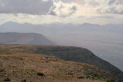 Scenic view of land and mountains against sky