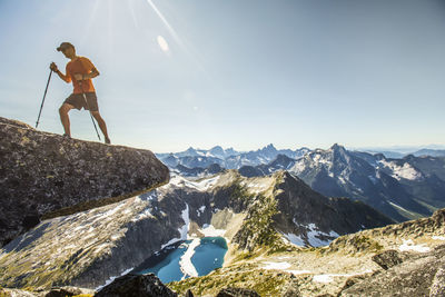 Trail runner hiking on mountain summit with views below.