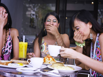 Cheerful friends talking while sitting at restaurant