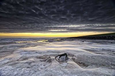 Scenic view of frozen sea against cloudy sky during sunset