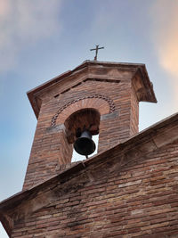 Detail of a small iron bell under a masonry arch of a church in san gimignano italy