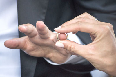 Cropped image of bride exchanging ring with groom during wedding